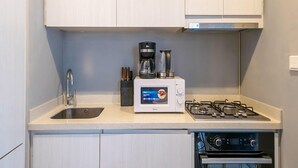 Una cocina compacta con un lavamanos, cafetera, microondas y estufa a gas.