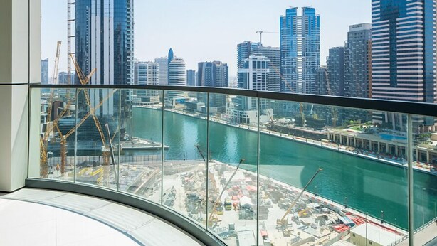 Un edificio alto con vista al paseo marítimo y grúas de construcción.