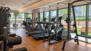 Un gimnasio con cintas de correr, máquinas elípticas y equipo de levantamiento de pesas.
