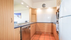 Una cucina compatta con pensili in legno, un lavello in acciaio inossidabile e un frigorifero bianco.