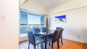 Zona pranzo con vista sul mare, un quadro appeso al muro e una finestra con persiane.
