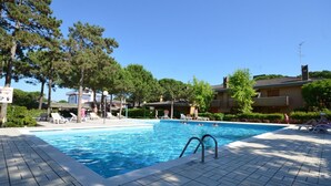 A swimming pool with a tiled deck, lounge chairs, and a sign indicating a 25°C water temperature. - Bright and cozy stay by the pool (Bibione)