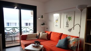 Una sala de estar moderna con un sofá rojo, una mesa de centro blanca y un balcón con vistas.