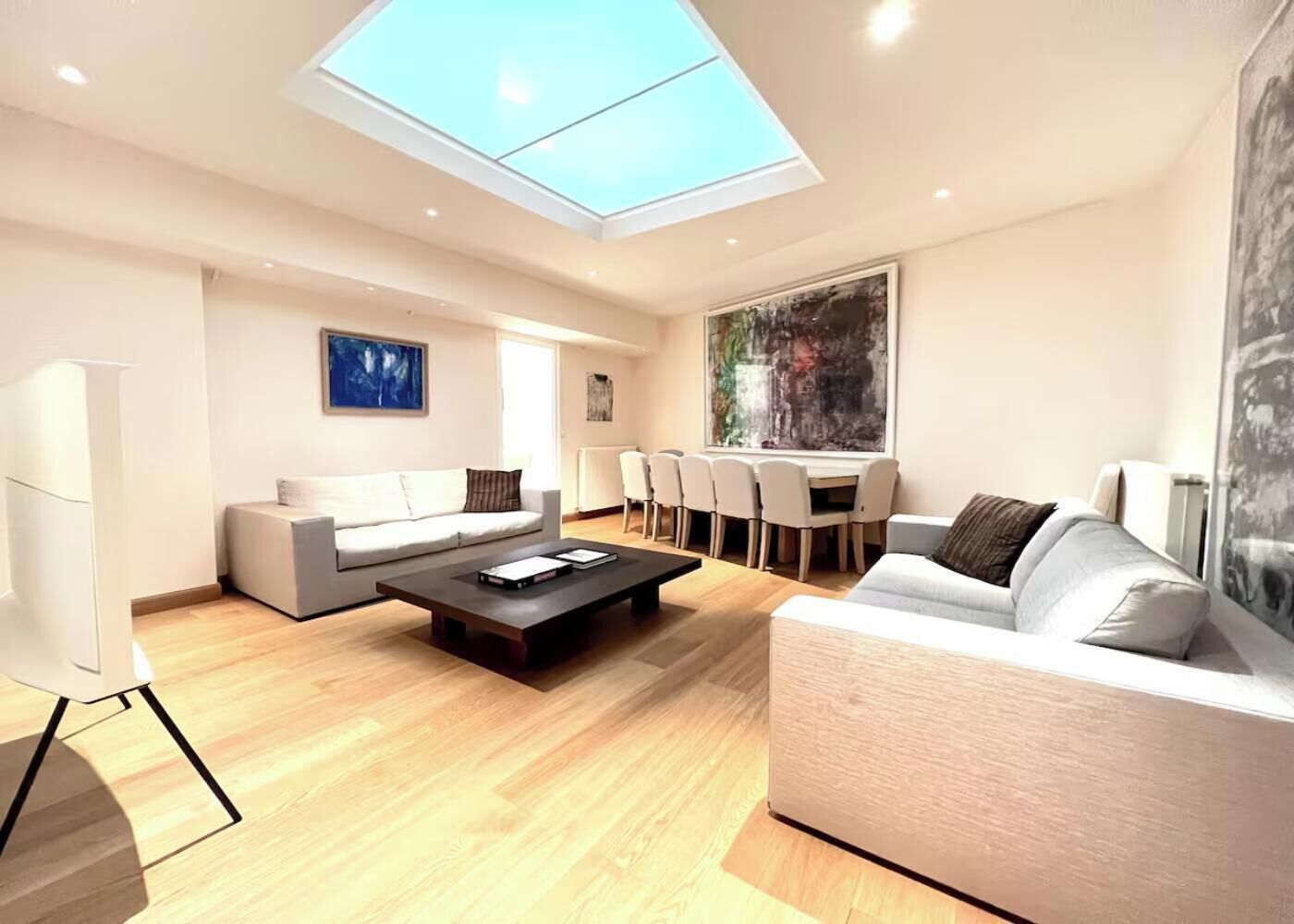 A modern living room with a skylight, two sofas, a coffee table, and a dining area with chairs.