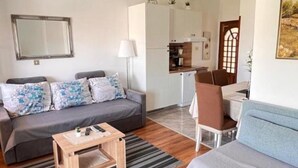 A compact living space with a sofa, a coffee table, a dining area, and a kitchen. - Apartments Valentinovo (Novi Vinodolski)