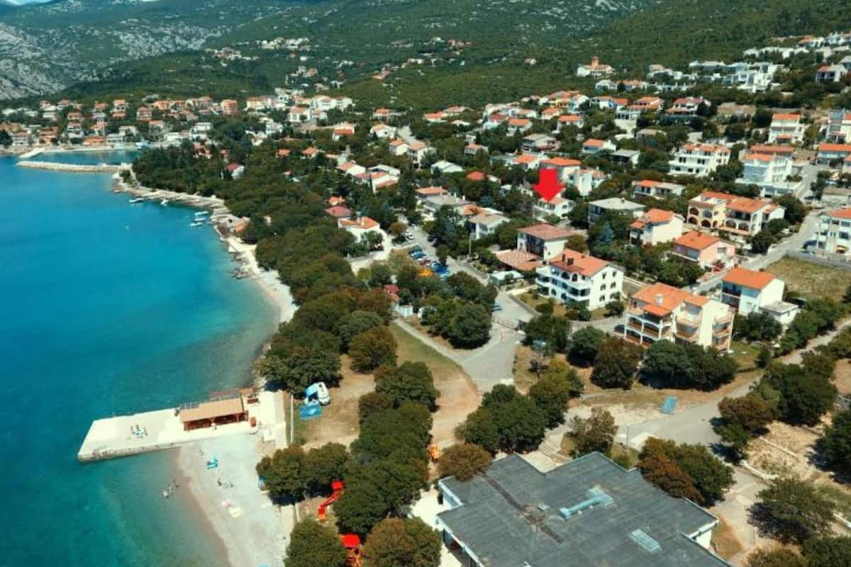 Luftaufnahme einer Küstenstadt mit Häusern, einem Strand und einem Steg.