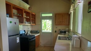 A compact kitchen with a refrigerator, stove, microwave, and sink.