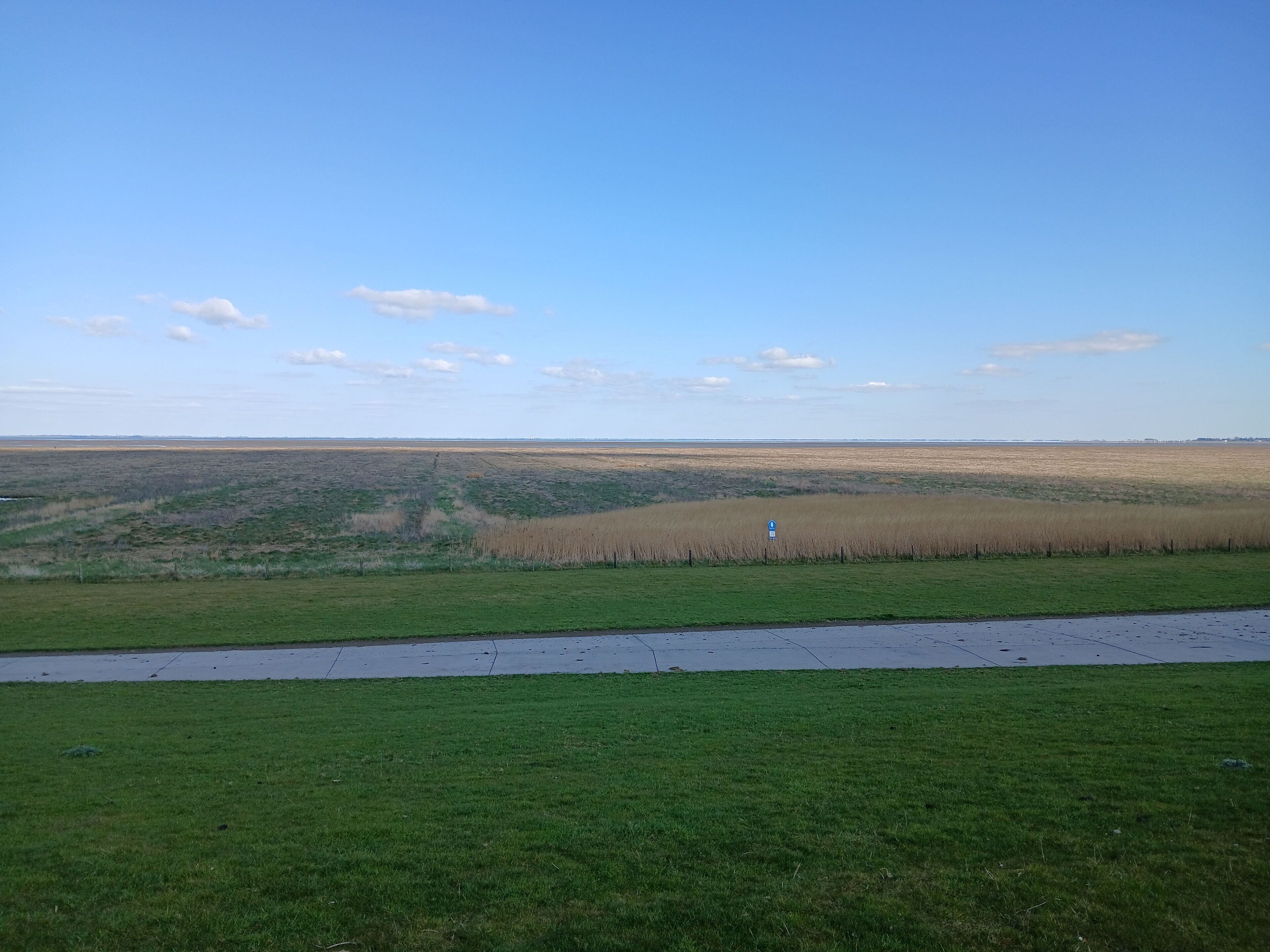 A flat landscape with a grassy foreground and a clear sky.