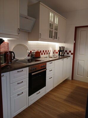 A modern kitchen with white cabinets, a stainless steel range, and a wooden countertop. - Single-story vacation home near the salt marshes! (Sande)