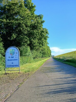 A road sign with text in a foreign language, surrounded by greenery and a clear sky. - Single-story vacation home near the salt marshes! (Sande)