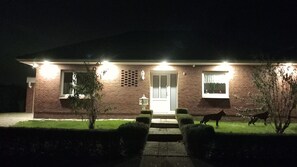 A house with a brick exterior, a front door, two windows, and a small garden with hedges. - Single-story vacation home near the salt marshes! (Sande)