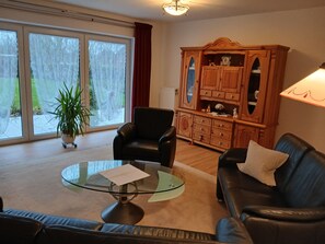 A living room with a glass coffee table, two leather sofas, a wooden cabinet, and a potted plant. - Single-story vacation home near the salt marshes! (Sande)