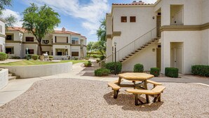 Un cortile con tavolo da picnic e panchine, circondato da edifici dallo stesso stile architettonico.