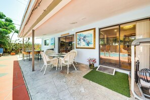 Un patio con porta vetrata che dà su una piscina, sedie in vimini e un tavolo.