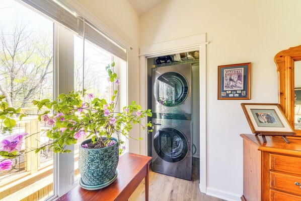 Ein Waschraum mit Waschmaschine und Trockner, einem Holzkabinet und einem Blumentopf mit Blumen.