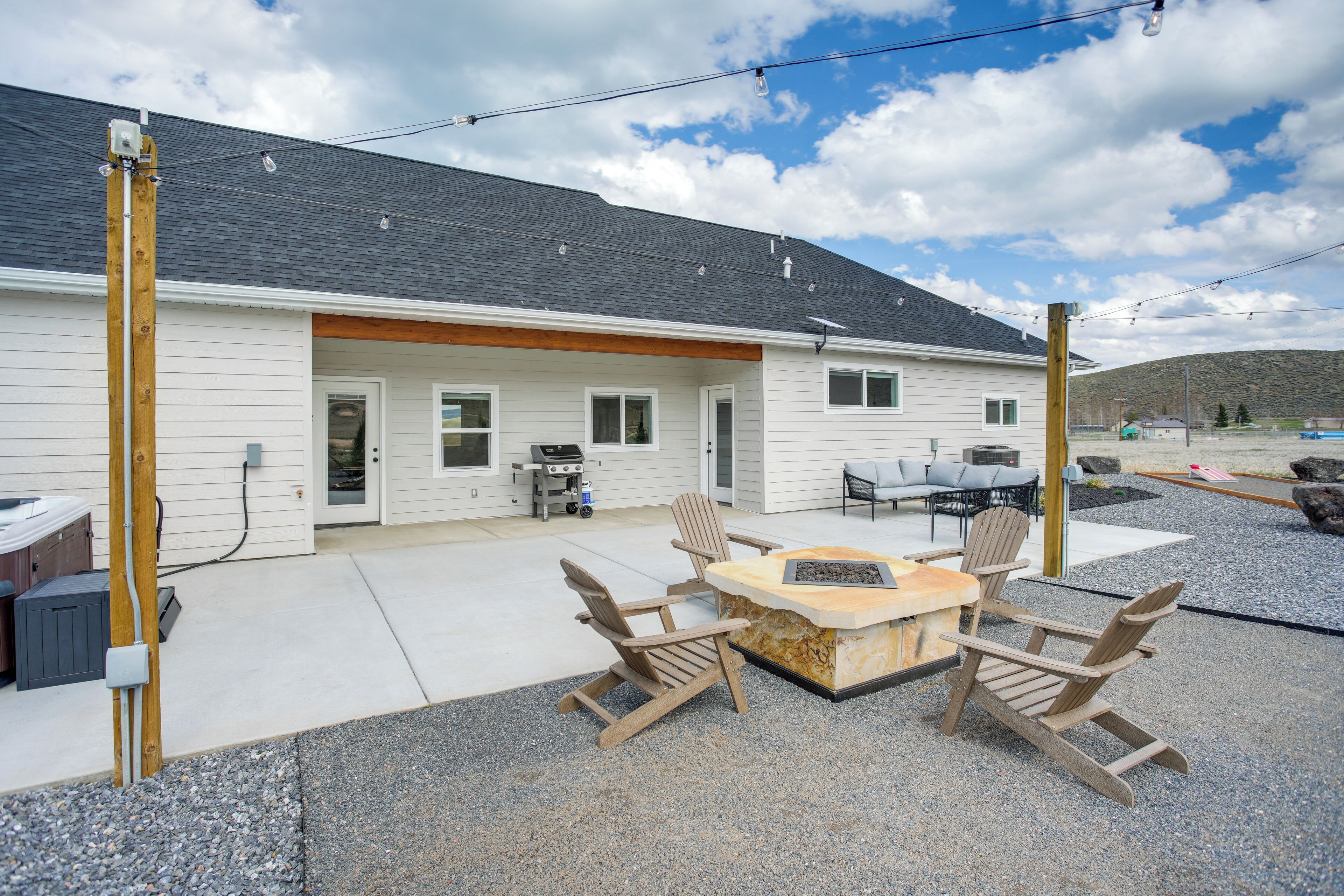 A house with a patio area featuring a fire pit and Adirondack chairs.