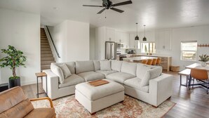 A modern living room with a sectional sofa, a coffee table, and a dining area with a table and chairs.