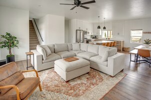 Uma sala de estar moderna com um sofá seccional, uma mesa de centro e um espaço de jantar com mesa e cadeiras.