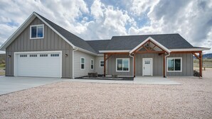 A modern two-story house with a garage, a covered porch, and a landscaped driveway.