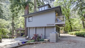 Una casa de dos pisos con balcón, rodeada de un bosque.