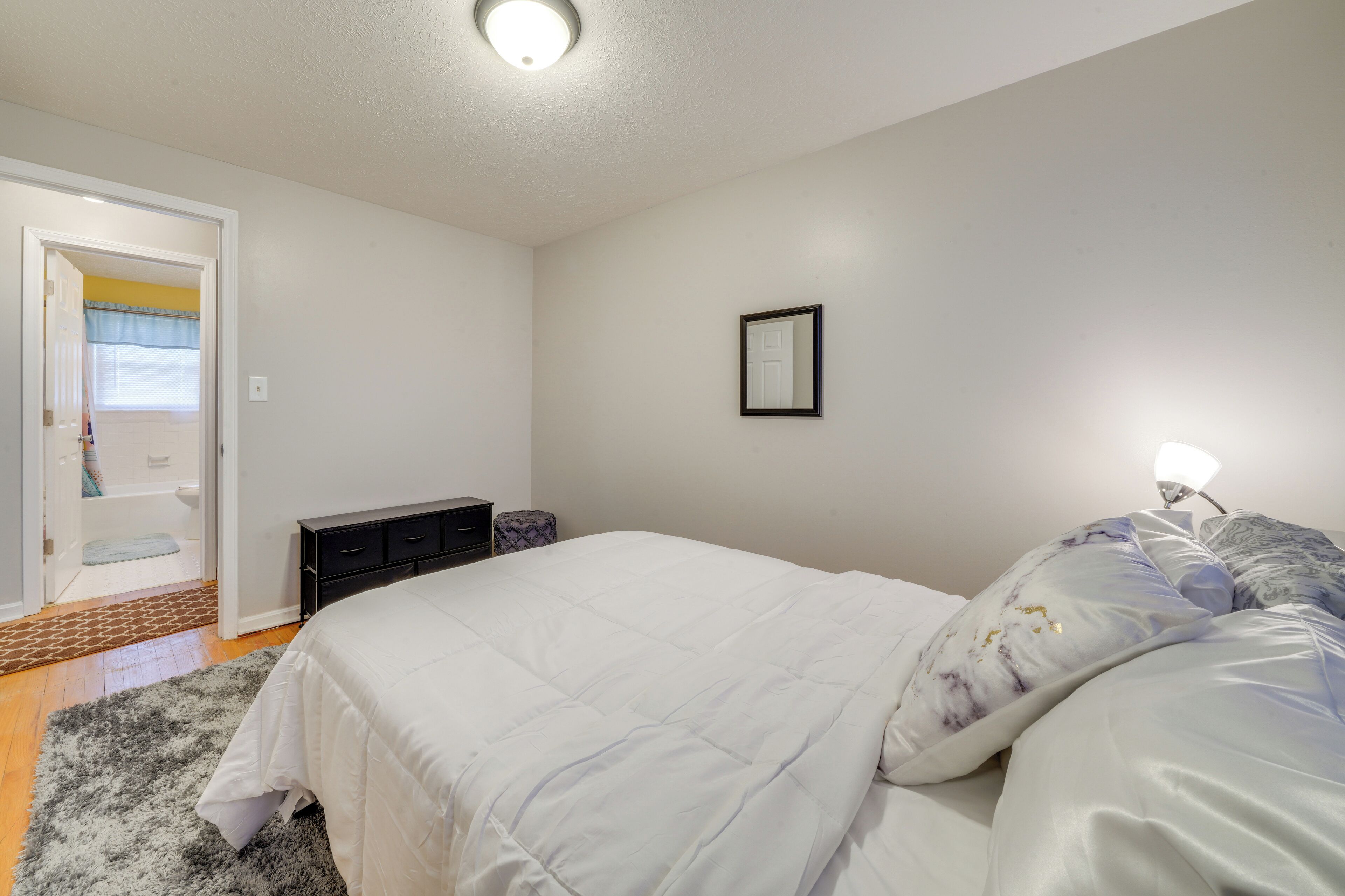 Un dormitorio con cama, mesita de noche y puerta que da a un baño.