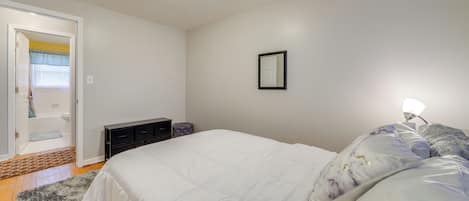 Un dormitorio con cama, mesita de noche y puerta que da a un baño.