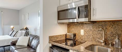 A modern kitchen with a built-in microwave, stainless steel sink, and a compact dishwasher.