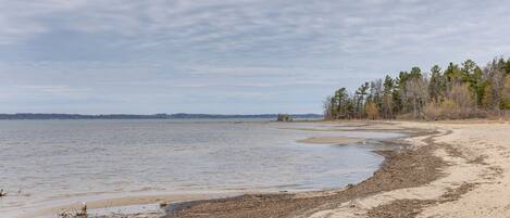 Ein Strand mit sandigem Ufer und ruhigem Wasser.