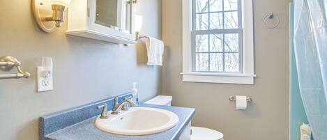 A bathroom with a sink, toilet, and a window.