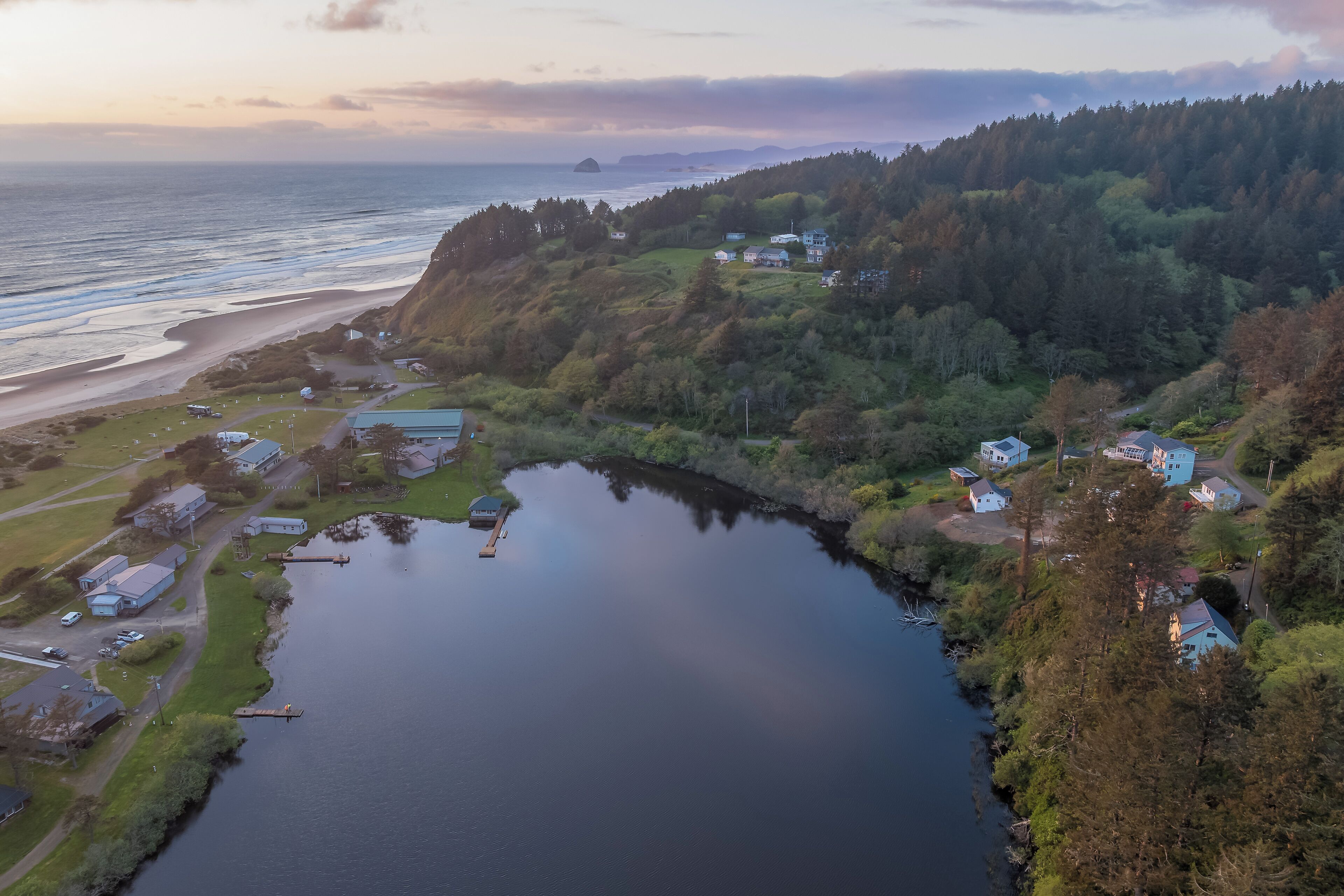 A coastal area with a lake, houses, and a forested hill.
