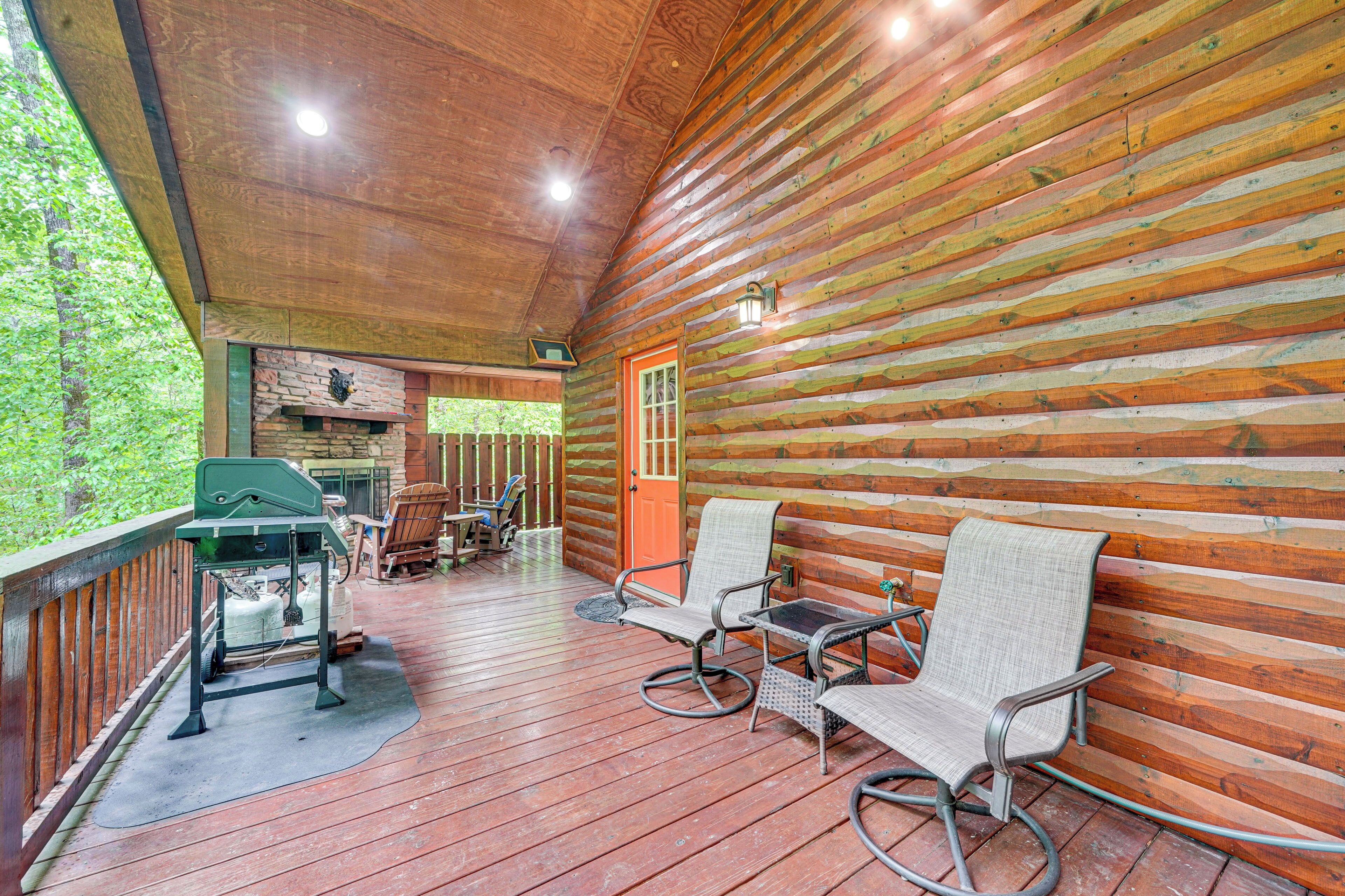 A wooden deck with a grill, two wicker chairs, and a table.