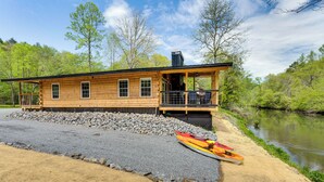 A wooden cabin with a porch and a covered deck, situated by a river with kayaks. - Relax Fireside! Creek Cabin 9 Mi to Dtwn Murphy (Murphy)