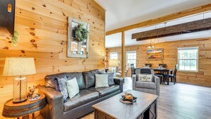 A cozy cabin interior with a leather sofa, a wooden coffee table, and a dining area with a table and chairs. - Relax Fireside! Creek Cabin 9 Mi to Dtwn Murphy (Murphy)