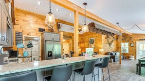 A kitchen with wooden walls, a central island with bar stools, a refrigerator, and pendant lighting. - Relax Fireside! Creek Cabin 9 Mi to Dtwn Murphy (Murphy)
