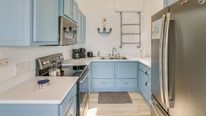 Una cocina con armarios azul claro, electrodomésticos de acero inoxidable y una alfombra pequeña en el suelo.