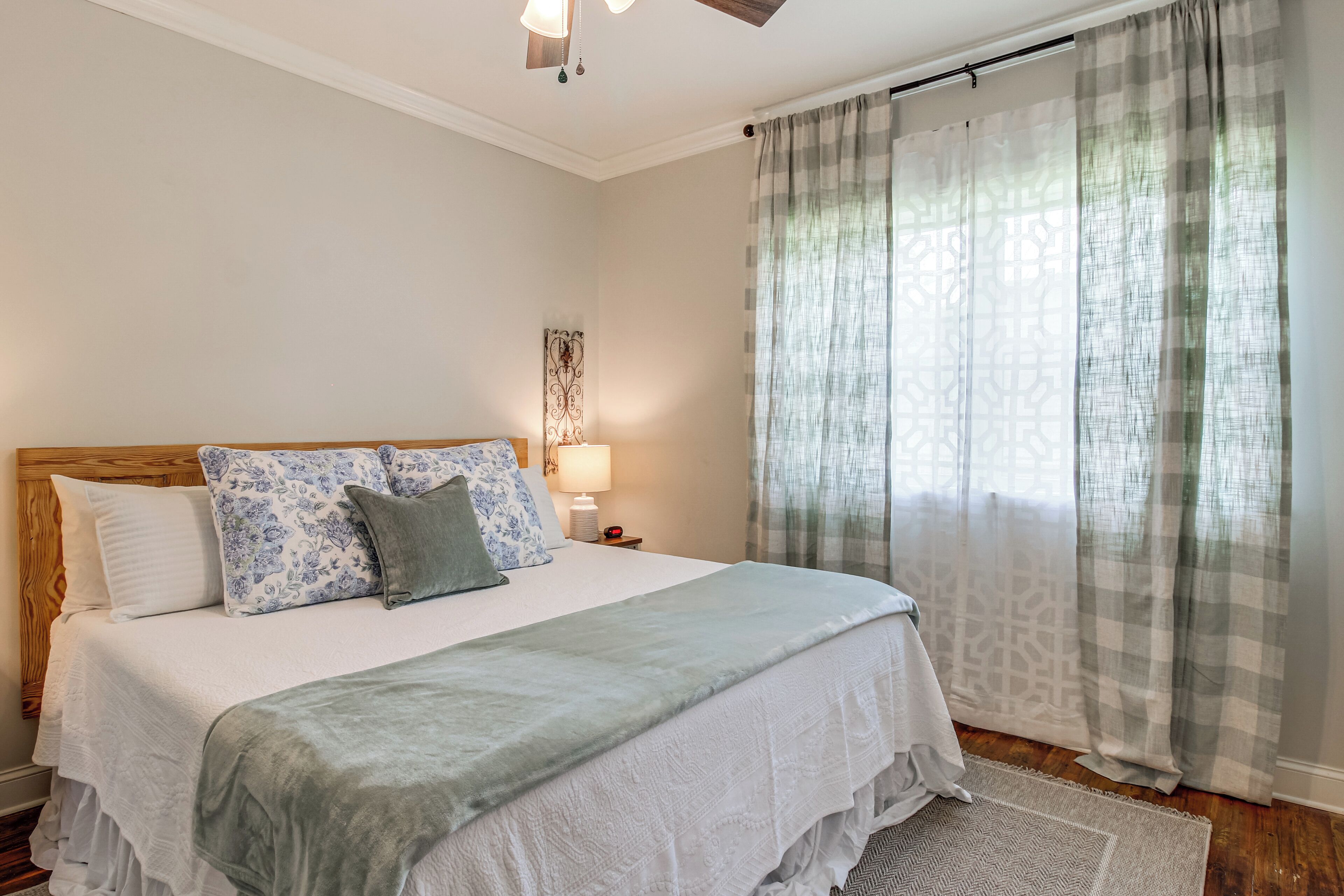 Un lit bien fait, avec une tête de lit en bois, une lampe de chevet et un coussin à motifs.
