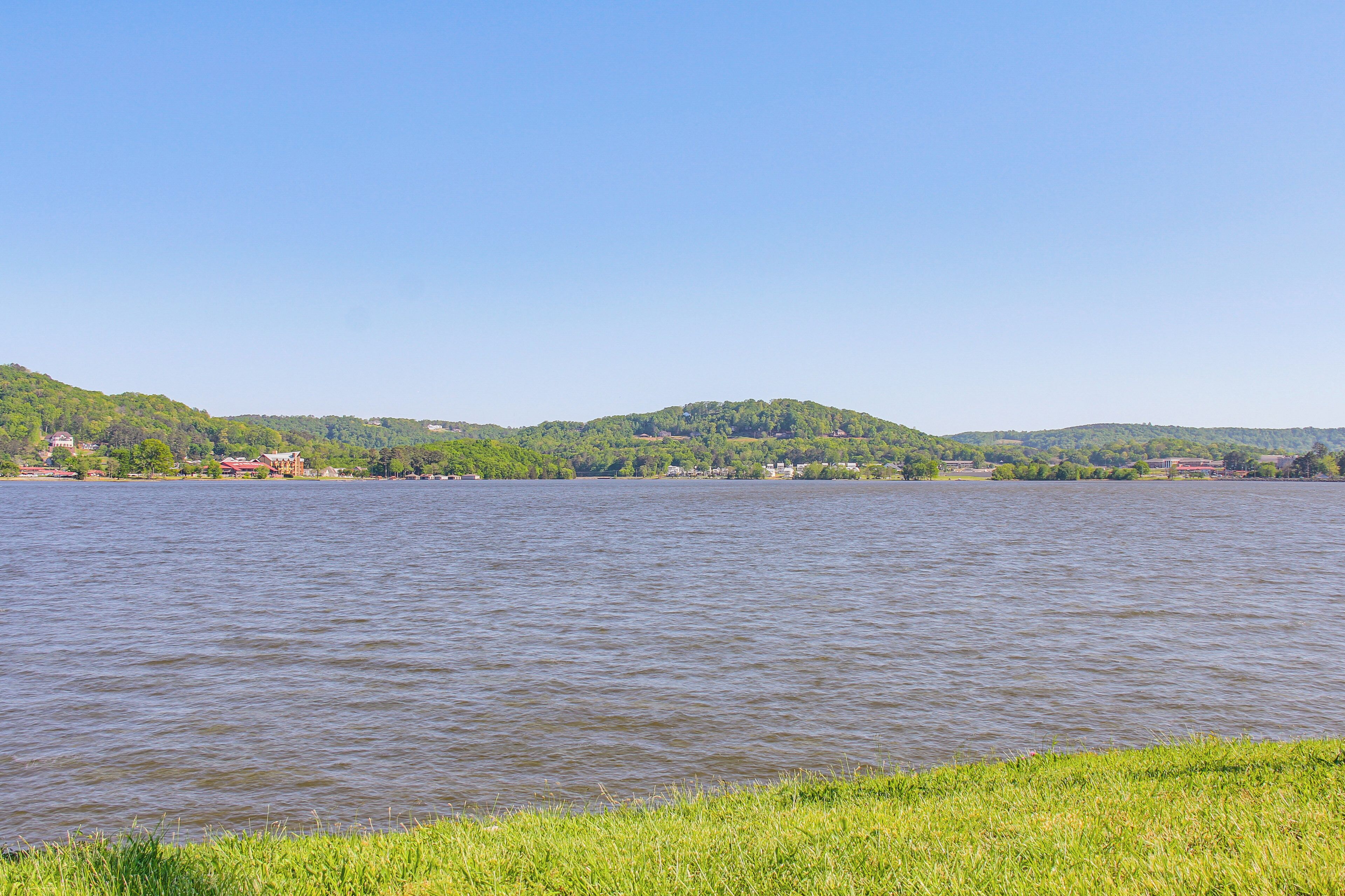 Un lac bordé d’une rive herbeuse, avec des collines en arrière-plan.