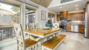 A modern kitchen with wooden cabinets, a marble countertop, and a dining area with a wooden table and chairs.