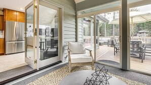 A modern kitchen with stainless steel appliances, a sliding glass door leading to a deck, and a cozy seating area with a cushioned chair.