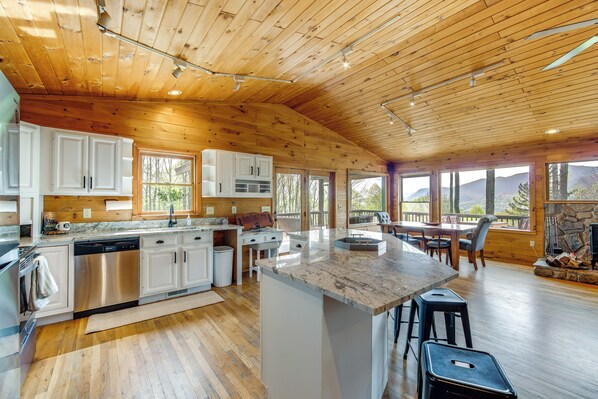 A spacious kitchen with wooden ceiling, white cabinets, and a large island with stools. - 10 Mi to Waynesville: Cabin w/ Hot Tub & Mtn Views (Balsam)