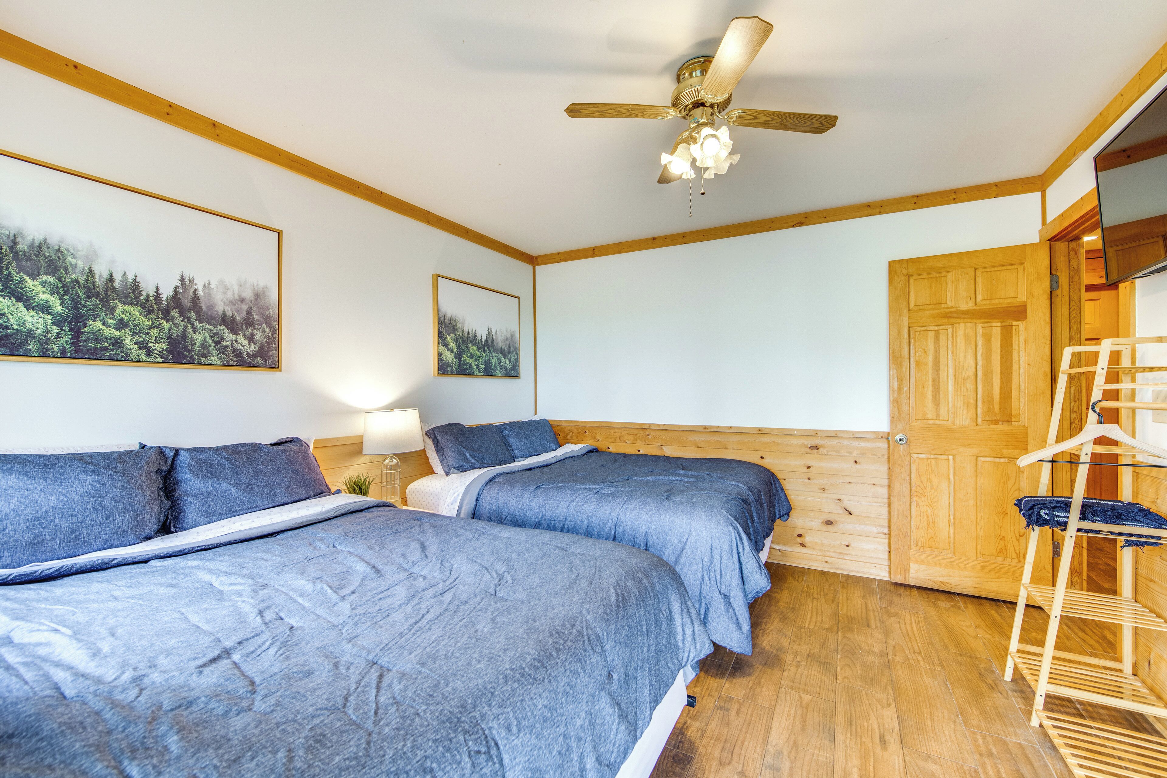 A bedroom with two beds, a wooden ceiling fan, and a wooden door.