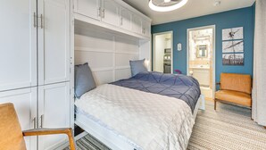 Une chambre à coucher avec un lit, une armoire blanche et une chaise.