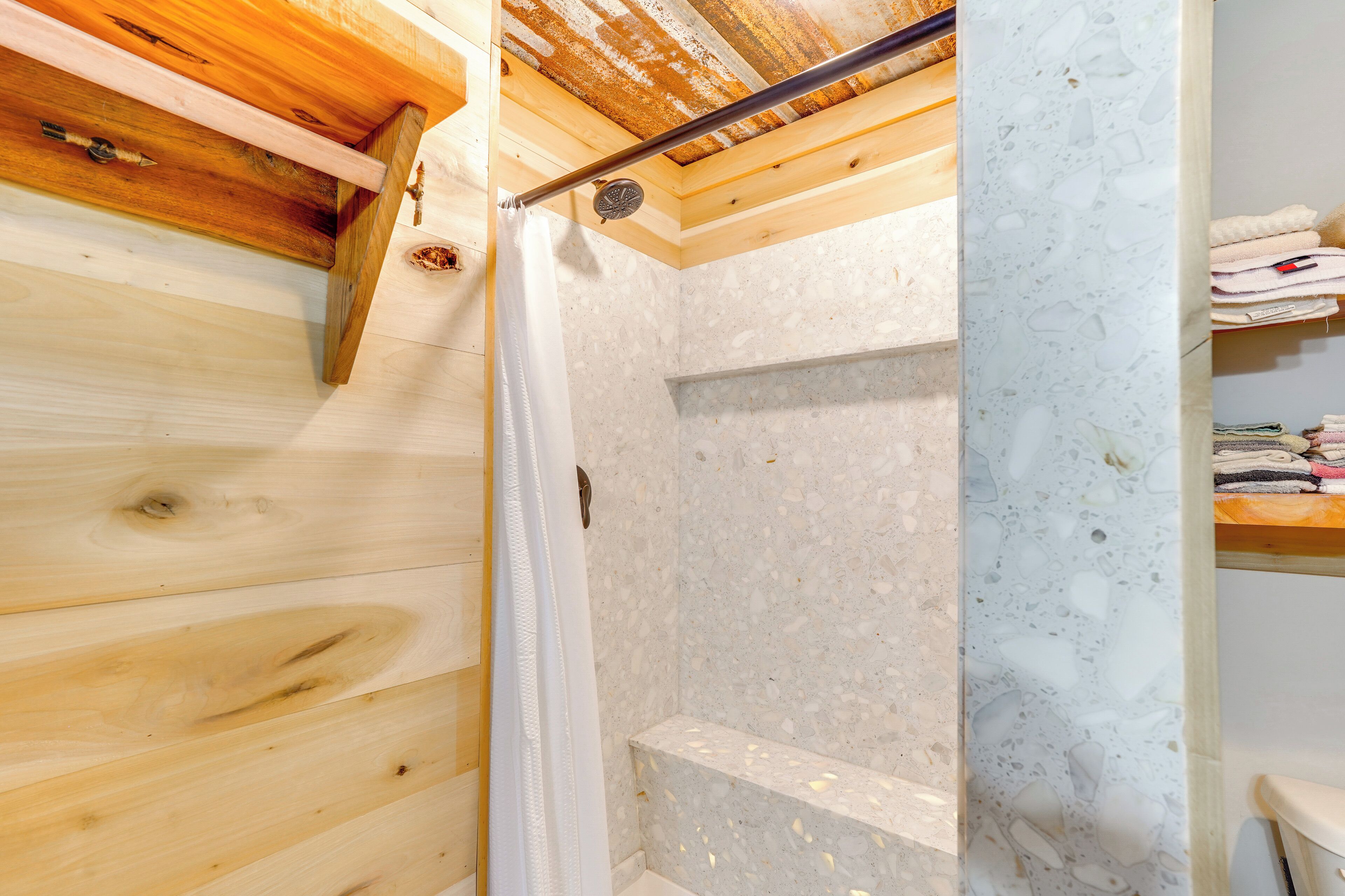 Ducha con techo de madera y pared de mármol.