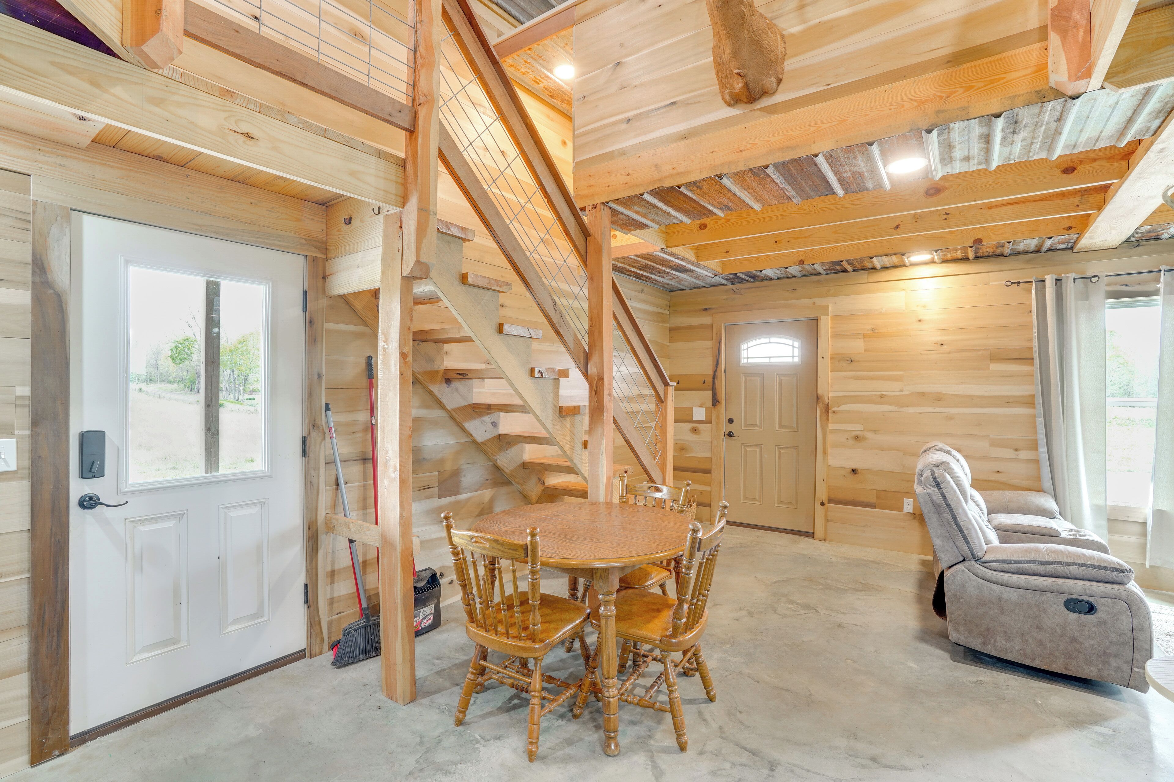 A wooden interior with a dining table and chairs, a massage chair, and a staircase.
