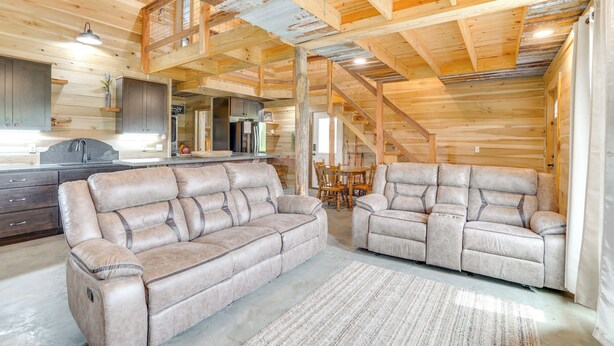 A spacious living area with two beige sofas, a dining table, and a kitchen in the background.