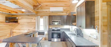 A compact kitchen with wooden walls, a central island, and modern appliances.