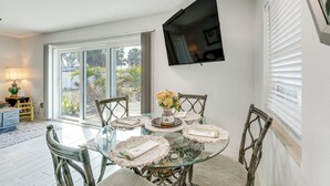 A dining area with a glass table, wicker chairs, and a vase of flowers. - Canal-front Home w/ Private Dock in North Port! (North Port)