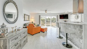 A modern living room with a large mirror, a sofa, a coffee table, and a TV mounted on the wall. - Canal-front Home w/ Private Dock in North Port! (North Port)