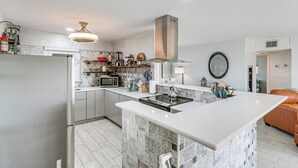 A modern kitchen with a central island, stainless steel appliances, and a hanging light fixture. - Canal-front Home w/ Private Dock in North Port! (North Port)