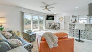 A spacious living area with a leather sofa, a dining table, and a kitchen area with a tiled backsplash. - Canal-front Home w/ Private Dock in North Port! (North Port)